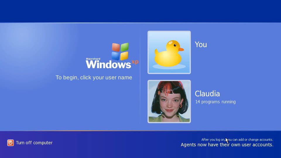 A blue Windows XP-style login screen titled "Macrohard Windows xp". Two users are listed: "You", shown with a yellow rubber duck, and "Claudia", shown with a photo of a smiling young woman with a black bob and red streaks, labelled "14 programs running". A caption at the bottom right reads "Agents now have their own user accounts."